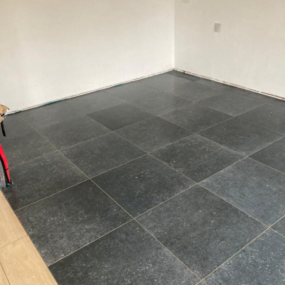 Plaatsen van tegels 60×60 Bleu Stone donker geschuurd in keuken te De Pinte