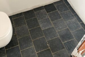 Plaatsen van tegels 20×20 Bleu Stone, donker geschuurd, halfsteenverband – hal en wc te De Pinte