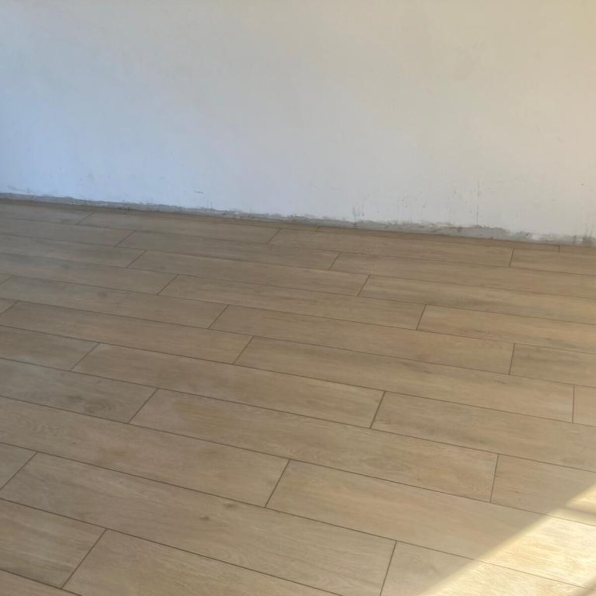 Plaatsen van parket-look tegels Viggo Arce Beige 20×120 in living en bureel te De Pinte